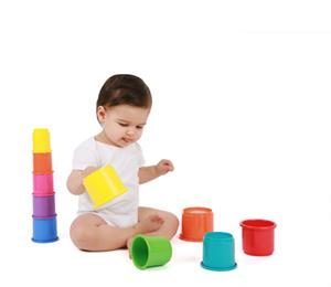 Young baby playing with coloured plastic cups for paediatric physiotherapist to observe